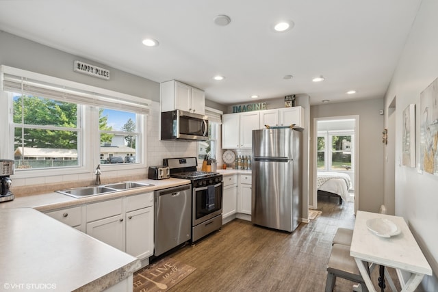 kitchen featuring a healthy amount of sunlight, sink, stainless steel appliances, and white cabinets