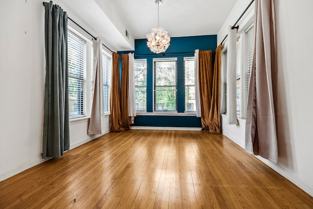 unfurnished room featuring wood-type flooring and a chandelier