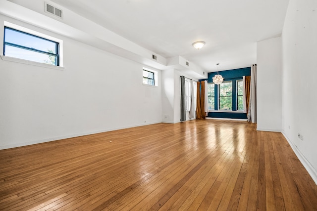 unfurnished room with light wood-type flooring and an inviting chandelier