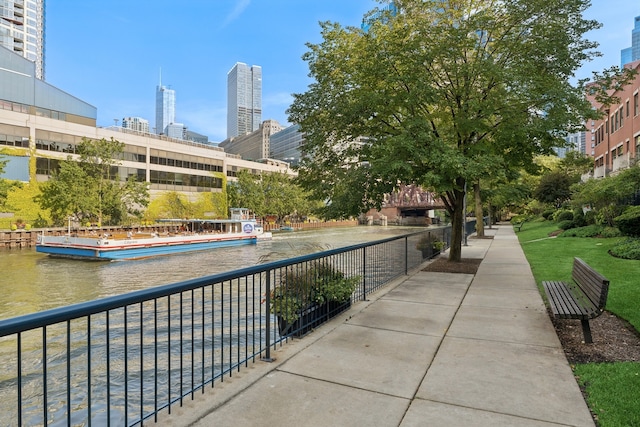 surrounding community with a water view and a lawn