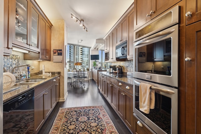 kitchen featuring pendant lighting, dark stone counters, dark wood-type flooring, sink, and black appliances