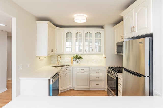 kitchen featuring sink, tasteful backsplash, white cabinetry, appliances with stainless steel finishes, and light wood-type flooring