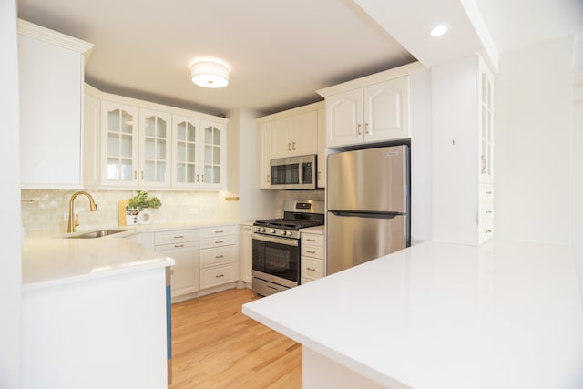 kitchen with stainless steel appliances, light wood-type flooring, sink, and white cabinetry