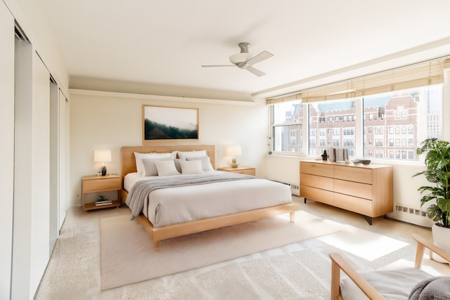 bedroom featuring light carpet, a closet, ceiling fan, and baseboard heating