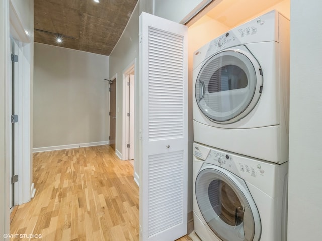 laundry room with stacked washer / drying machine and light hardwood / wood-style floors