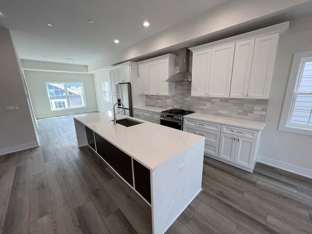 kitchen featuring wall chimney range hood, white cabinets, appliances with stainless steel finishes, and sink