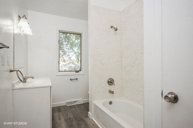 full bathroom featuring tiled shower / bath, hardwood / wood-style floors, toilet, vanity, and a textured ceiling