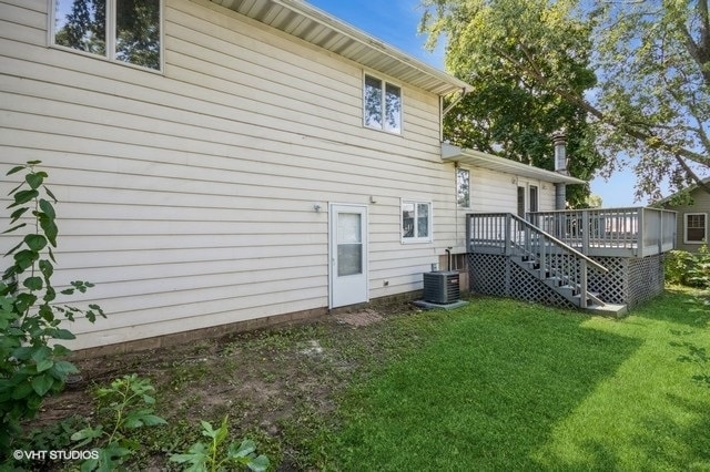 rear view of house with a yard, a deck, and central air condition unit