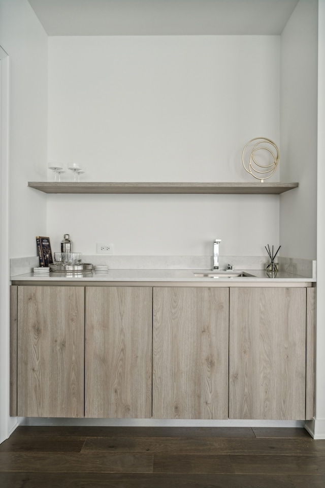 bar featuring light brown cabinetry, sink, and dark hardwood / wood-style flooring