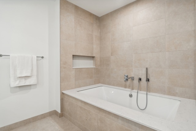 bathroom with tiled bath and tile patterned floors