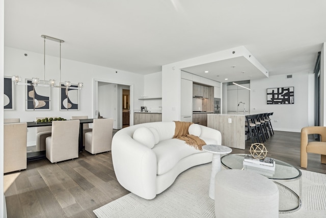 living room with sink, a chandelier, and hardwood / wood-style floors