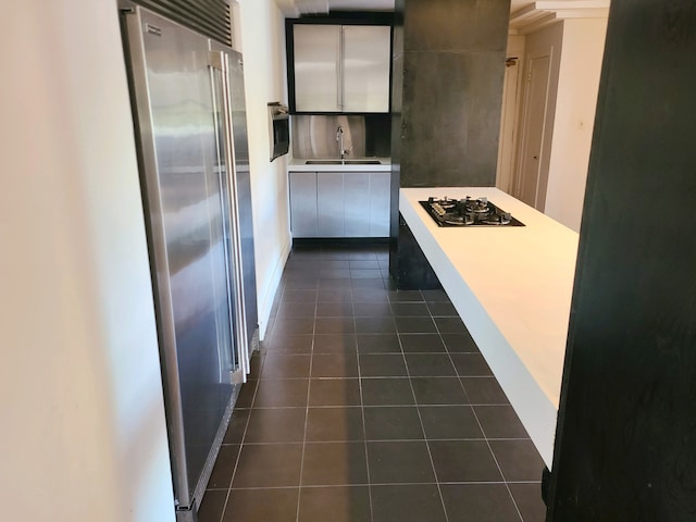 kitchen featuring white cabinetry, gas stovetop, dark tile patterned floors, sink, and high quality fridge