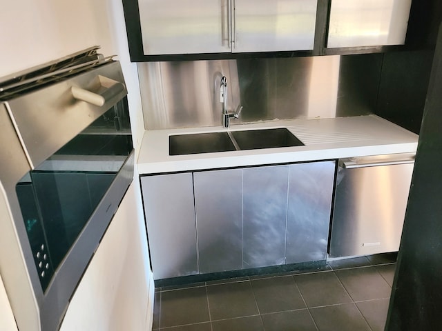 kitchen featuring dishwasher, dark tile patterned flooring, and sink