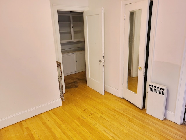 unfurnished bedroom with radiator, a closet, and light wood-type flooring