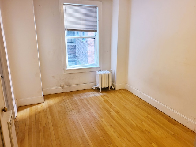 unfurnished room with radiator heating unit and light hardwood / wood-style flooring