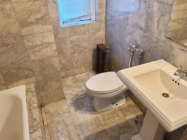 bathroom featuring tile walls, toilet, radiator, and a washtub