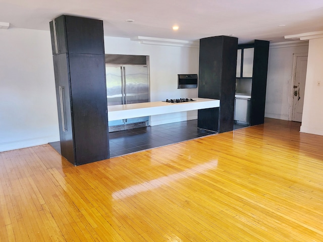 kitchen featuring crown molding, light wood-type flooring, stainless steel built in refrigerator, and black gas cooktop