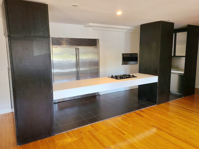 kitchen with built in refrigerator, wood-type flooring, and black gas cooktop