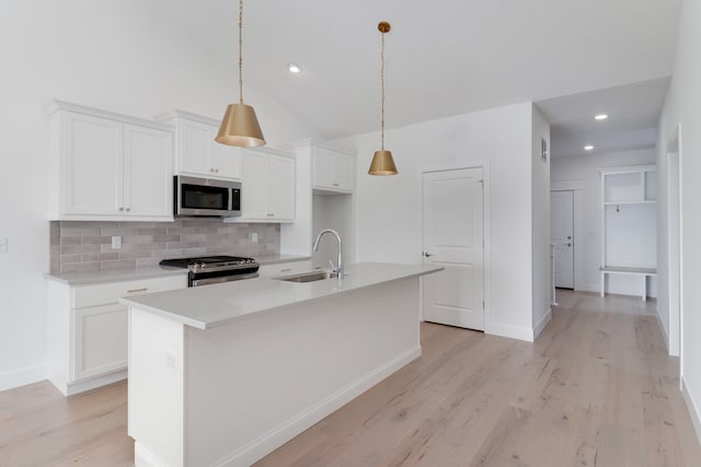 kitchen with white cabinets, light wood-type flooring, stainless steel appliances, sink, and a center island with sink