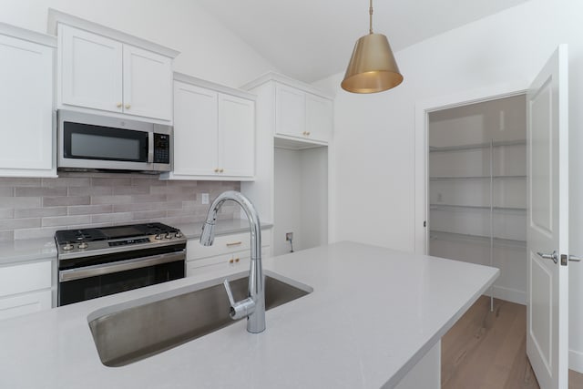 kitchen with pendant lighting, stainless steel appliances, sink, light wood-type flooring, and white cabinets