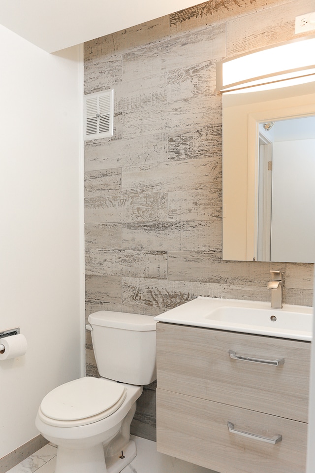 bathroom with vanity, toilet, and tile walls