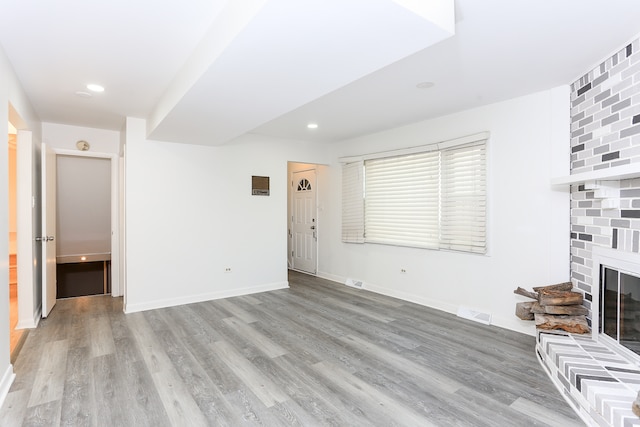 unfurnished living room featuring light hardwood / wood-style flooring and a brick fireplace