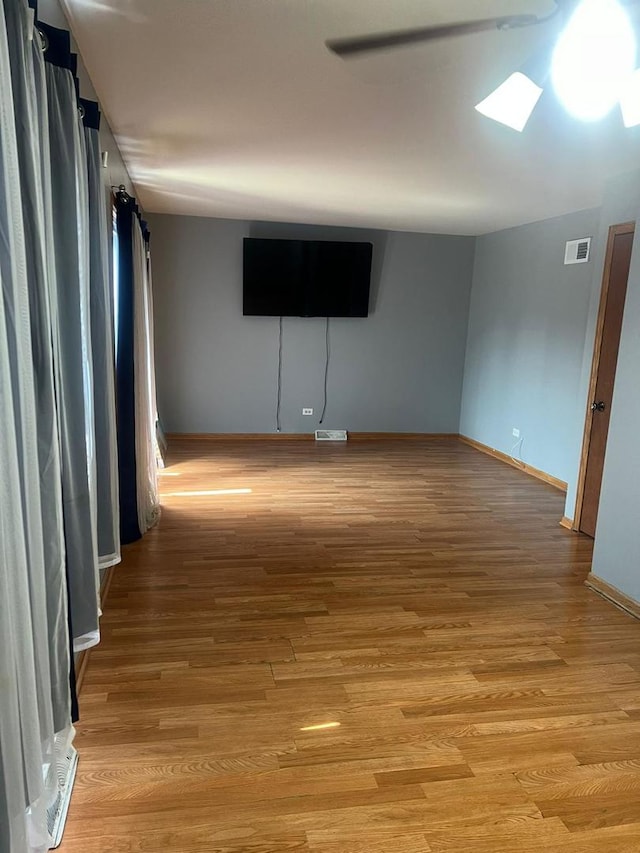 unfurnished room featuring light wood-type flooring, a skylight, and ceiling fan