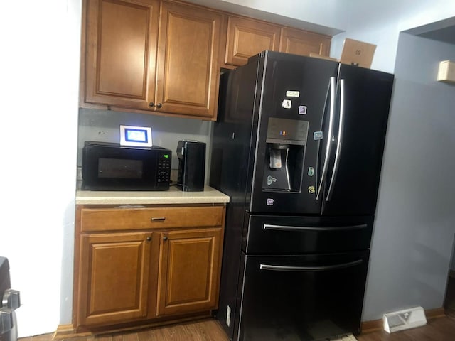 kitchen with black appliances and light hardwood / wood-style floors