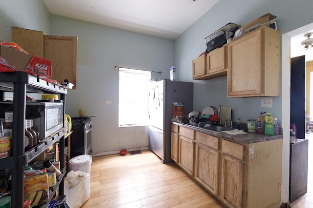 kitchen featuring light wood-type flooring, stainless steel refrigerator, white gas range oven, and sink