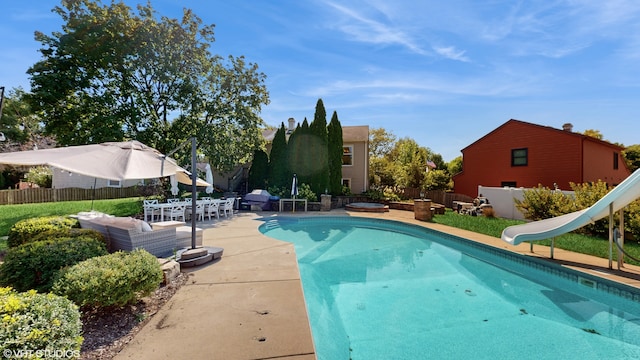 view of pool with a water slide and a patio area