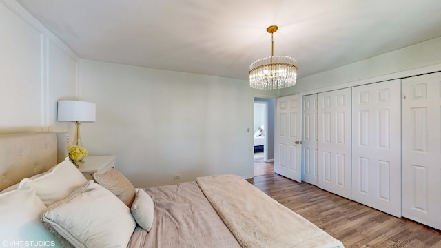 bedroom with wood-type flooring, a notable chandelier, and a closet