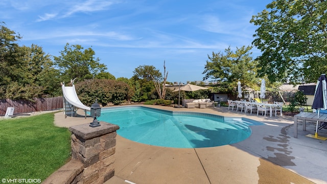 view of swimming pool with a yard, a water slide, and a patio area