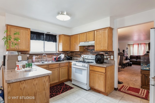 kitchen featuring decorative backsplash, white gas range, light colored carpet, and sink