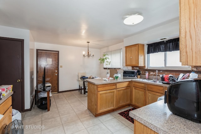 kitchen featuring a chandelier, sink, kitchen peninsula, hanging light fixtures, and backsplash