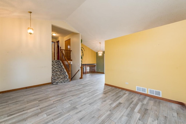 unfurnished room featuring a notable chandelier, lofted ceiling, and light hardwood / wood-style flooring