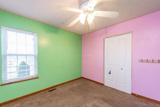 unfurnished bedroom with ceiling fan, a closet, carpet floors, and a textured ceiling