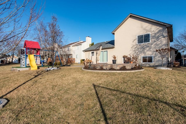 rear view of house featuring a playground and a yard