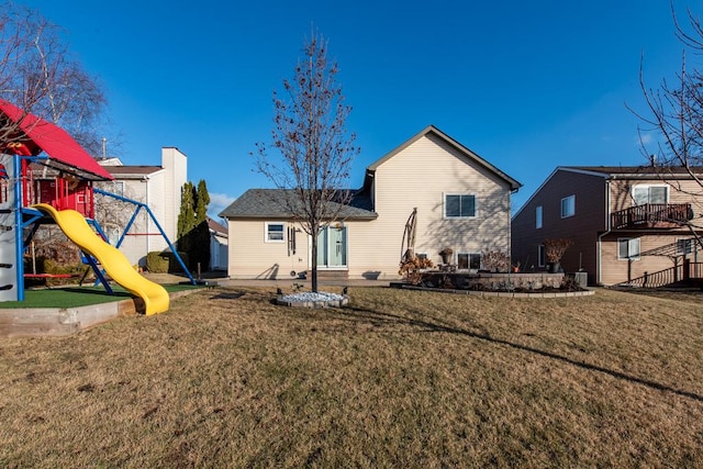 rear view of property with a playground and a yard