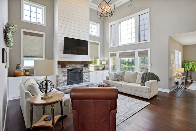 living room featuring a healthy amount of sunlight, a fireplace, a chandelier, and a high ceiling