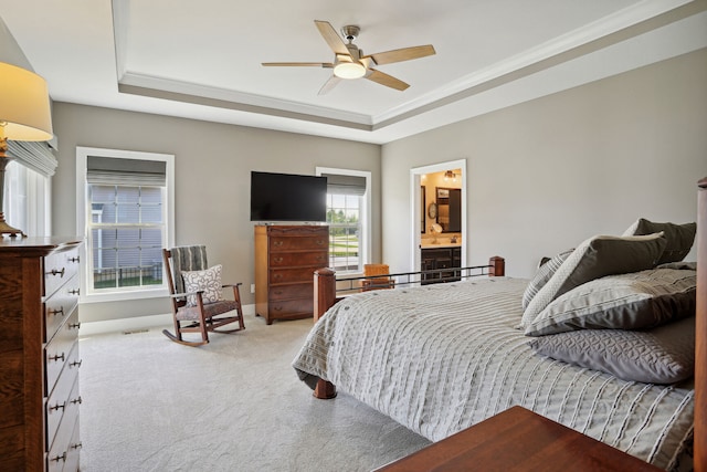 carpeted bedroom with ceiling fan, a raised ceiling, crown molding, and connected bathroom