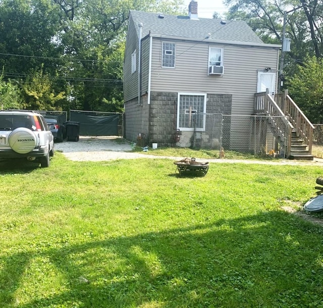 back of house featuring a fire pit, roof with shingles, a chimney, cooling unit, and a yard