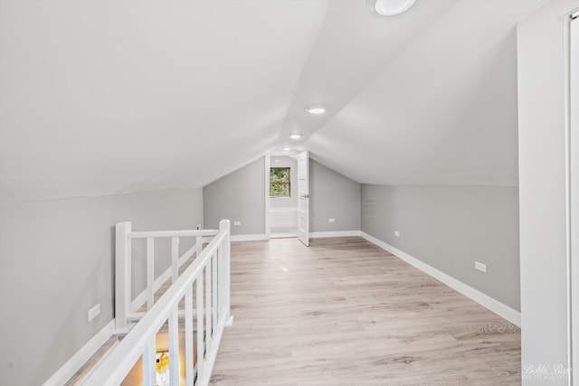 additional living space with light hardwood / wood-style flooring and vaulted ceiling