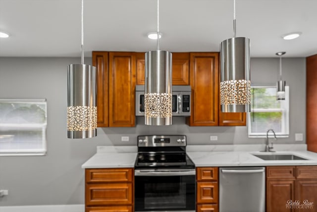 kitchen featuring light stone countertops, appliances with stainless steel finishes, pendant lighting, and sink