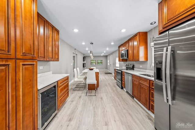 kitchen featuring hanging light fixtures, sink, wine cooler, light hardwood / wood-style flooring, and stainless steel appliances