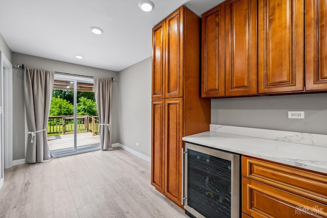 kitchen with light wood-type flooring, light stone countertops, and wine cooler