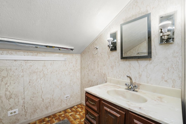 bathroom featuring vanity, a textured ceiling, and vaulted ceiling