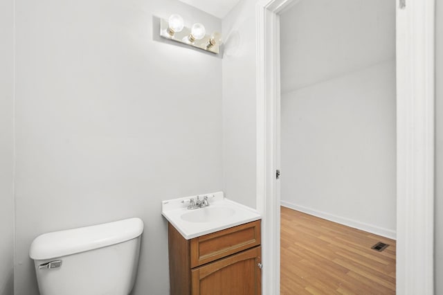 bathroom featuring wood-type flooring, vanity, and toilet