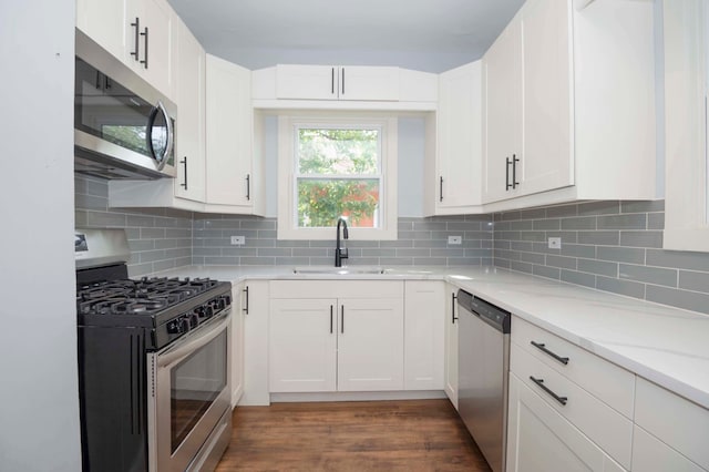 kitchen featuring sink, backsplash, white cabinetry, stainless steel appliances, and dark hardwood / wood-style flooring