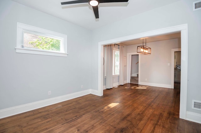 empty room featuring a wealth of natural light, ceiling fan, and dark hardwood / wood-style flooring