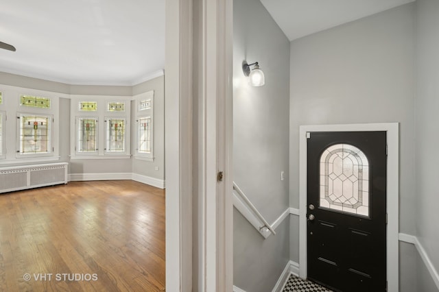 entryway featuring hardwood / wood-style floors, crown molding, and radiator heating unit